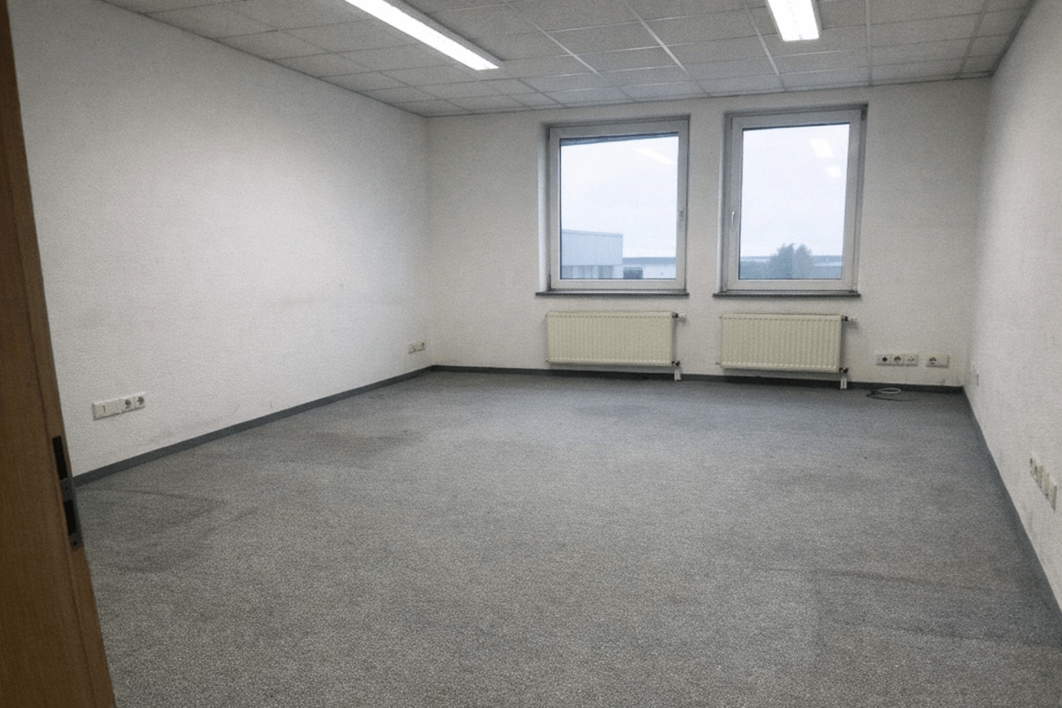 Leere Praxisräume mit abgebauter Anmeldung und gestapelten Transportkisten am Ausgang