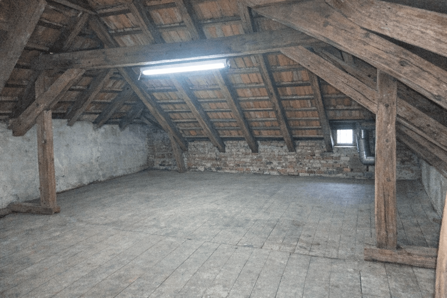 Freier Dachboden mit sichtbaren Balken und leerer Stellfläche entlang der Wände