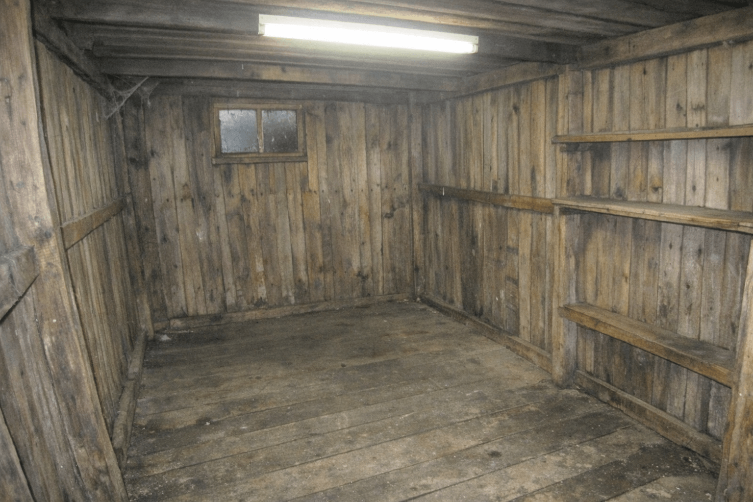 Gartenhaus mit leer geräumten Regalbrettern und zusammengelegten Altgeräten vor der Tür