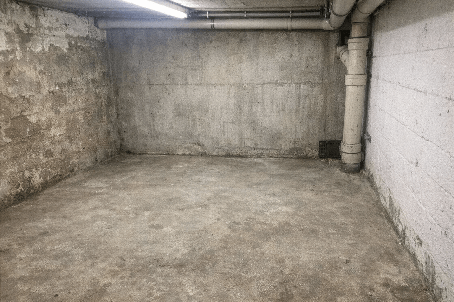 Leerer Keller mit freigeräumten Regalen und sauber gefegtem Betonboden